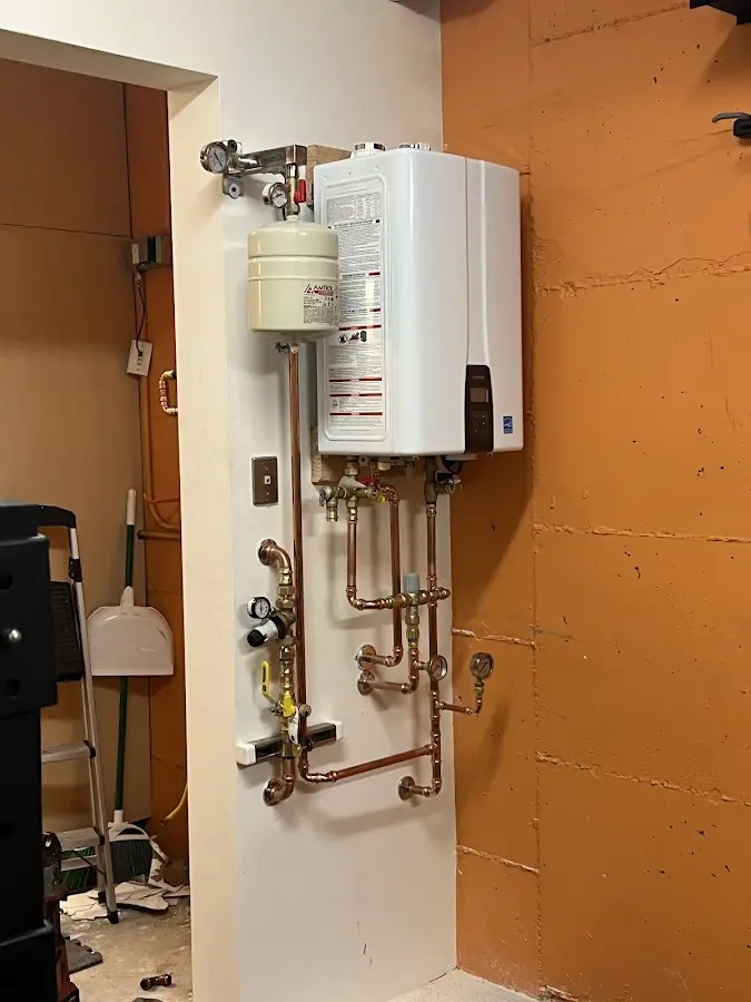 Plumbing technician inspecting water heater connections in Nowthen
